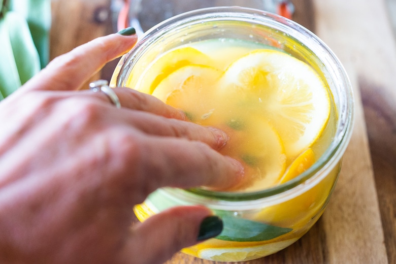 How to Preserve Lemons- a simple easy way to preserve lemons that only takes 10 minutes of hands-on time before letting mother nature take its course. Use in dressings, marinades, Middle Eastern Dishes and salad to add a burst of flavor. #preservedlemons