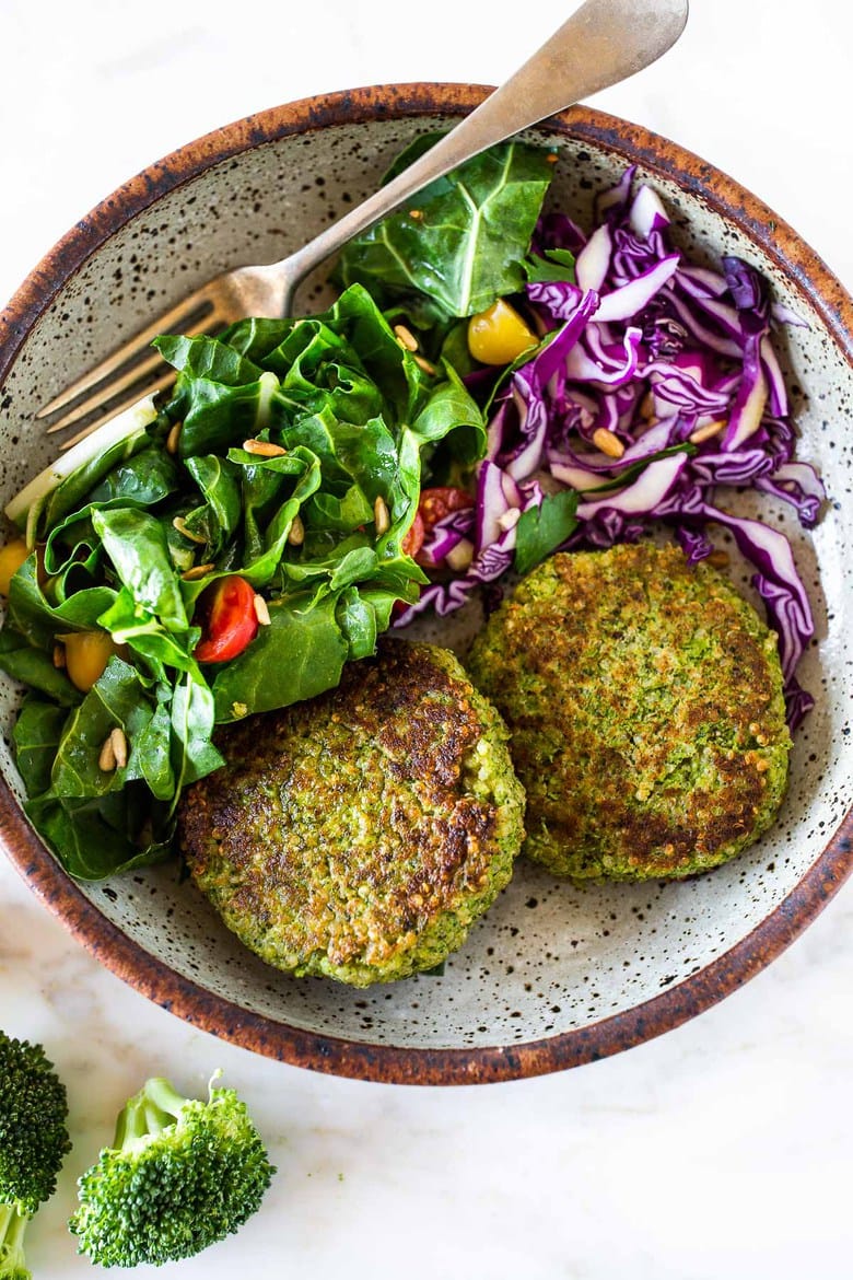 crispy broccoli quinoa cakes in serving dish with side salad and cabbage.