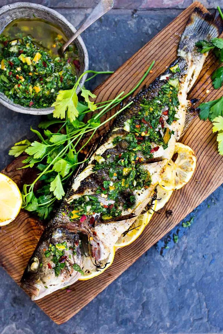 How to grill a whole fish (Branzino) topped with the most flavorful Preserved Lemon Gremolata, (Zesty Herb Sauce) in about 30 minutes flat! A simple easy Mediterranean dinner! #branzino #grilledfish #wholefish #grilledbranzino