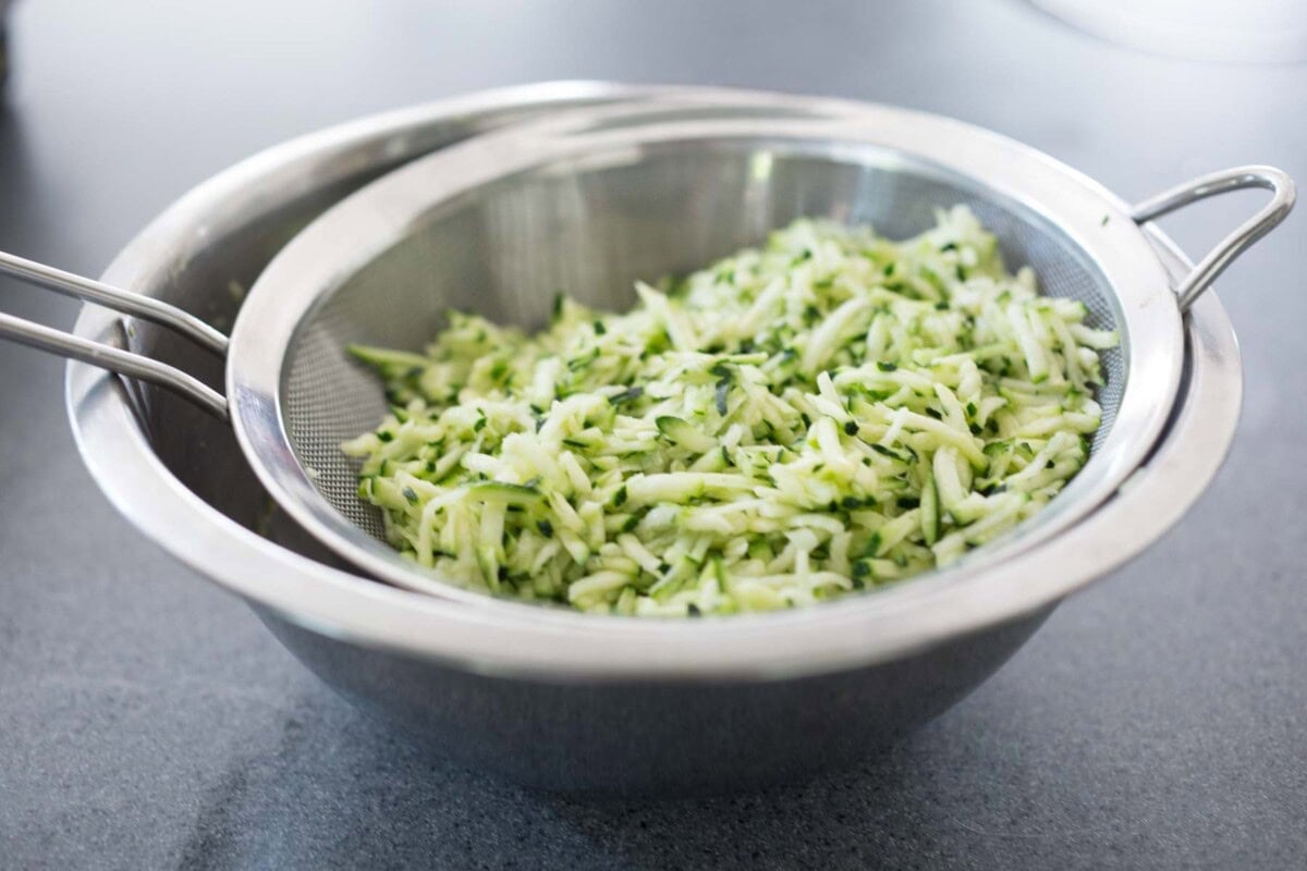 straining the liquid for zucchini fritters