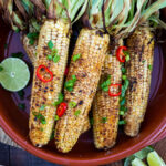 This Indian Masala Street Corn hails from the streets of Bombay. It's lathered with ghee and garam masala spice- a simple easy summer side dish to add to your next Indian feast! #grilledcorn #masalacorn #indiancorn