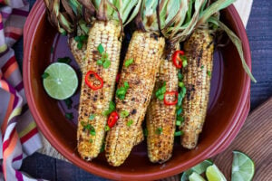 This Indian Masala Street Corn hails from the streets of Bombay. It's lathered with ghee and garam masala spice- a simple easy summer side dish to add to your next Indian feast! #grilledcorn #masalacorn #indiancorn
