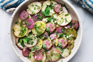 This French Potato Salad is loaded up with fresh herbs - tarragon, parsley and chives and dressed in the most flavorful dijon vinaigrette. It's vegan, with no mayo, and easy. to make! #herbedpotatosalad #frenchpotatosalad #veganpotatosalad