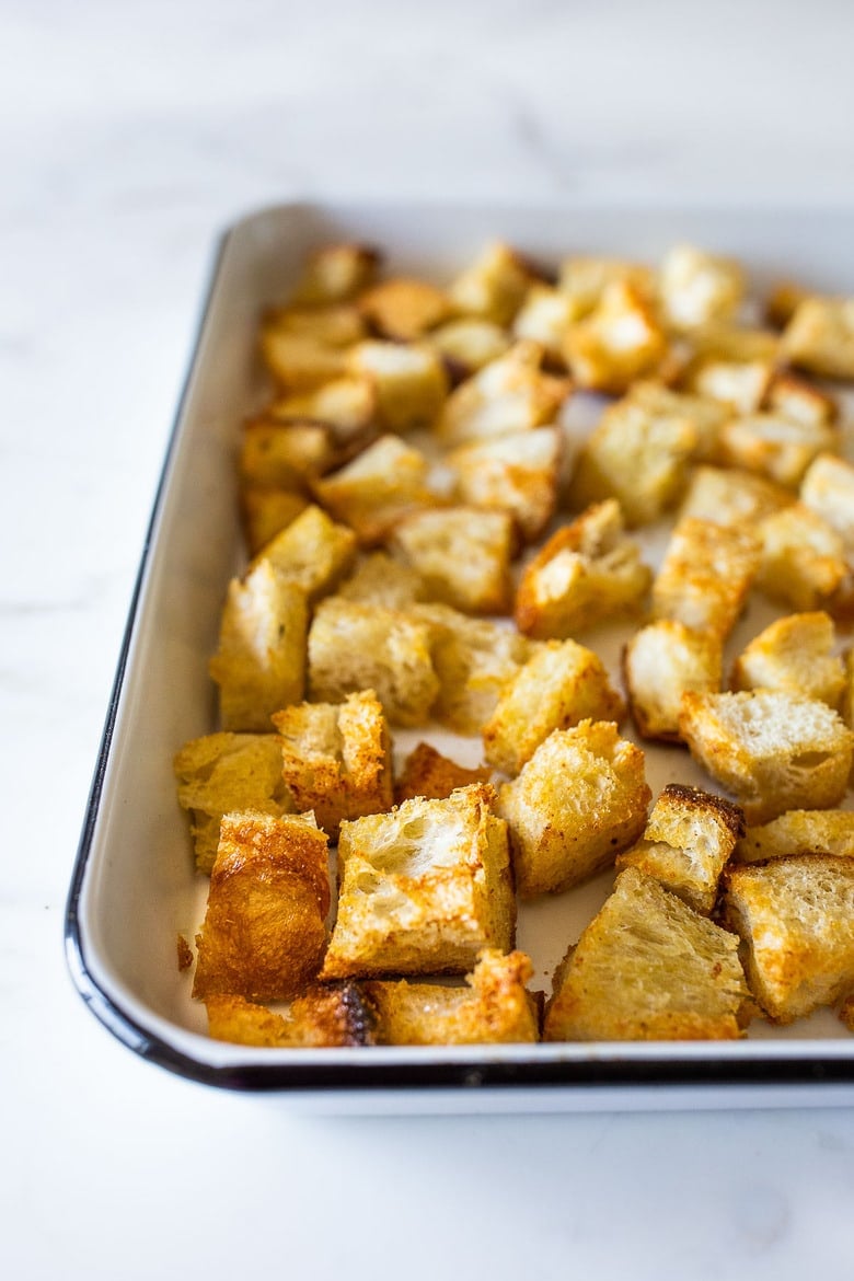 cubed and baked homemade sourdough croutons on baking sheet, golden and crispy.
