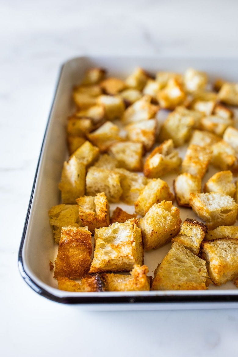 cubed and baked homemade sourdough croutons on baking sheet, golden and crispy. 