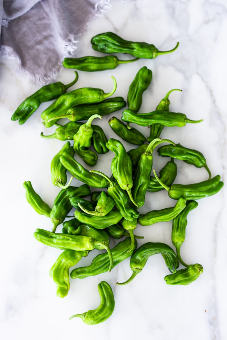 A simple flavorful recipe for Blistered Shishito Peppers with crispy garlic and Furikake Seasoning- a delicious appetizer that can be made in minutes! Vegan. #shishito #blistered #peppers #furikake 