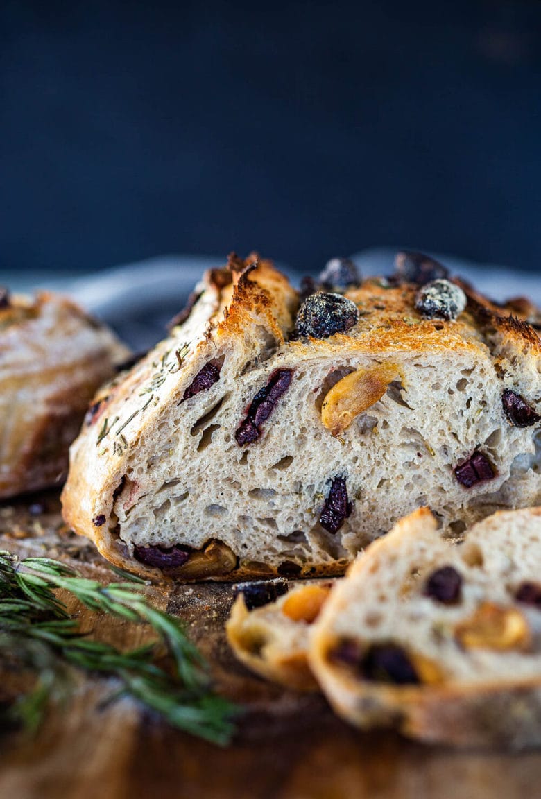 How to make Crusty Sourdough Bread, infused with rosemary, roasted garlic and olives that requires no kneading and rises overnight. Made with sourdough starter instead of yeast! #sourdoughbread