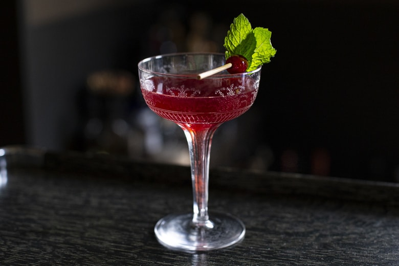 A festive holiday cocktail made with assertive rye whiskey, enlivened with tart cranberry & lemon, the whole softened by 2 festive liqueurs; garnished with a bit of holiday fruit, or (depending on how you've been this year) - a lump of "coal".