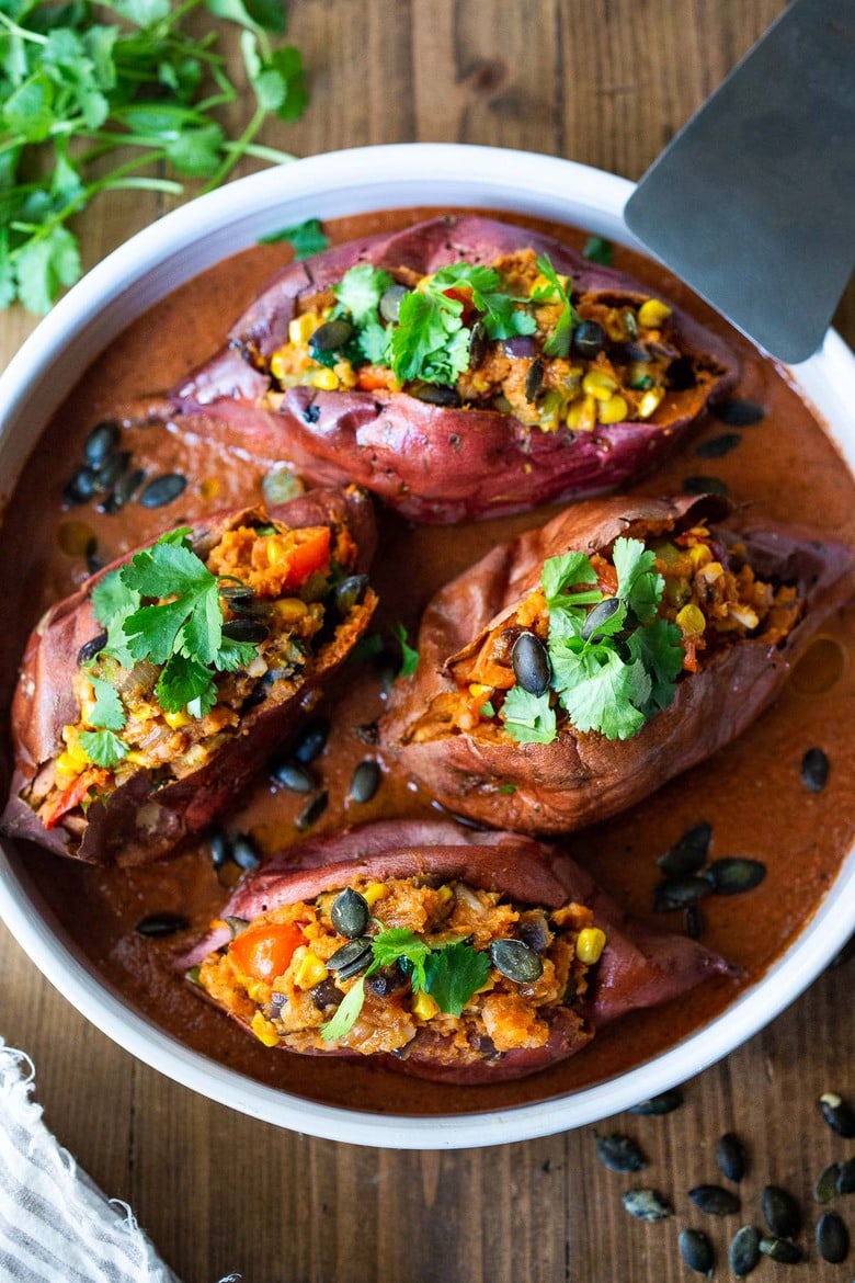  Baked Sweet Potatoes are loaded up with healthy veggies and infused with Oaxcan flavors, served over optional Mole Sauce. Healthy, flavorful and perfect for Sunday meal prep. Vegan-adaptable! Gluten-free. #bakedsweetpotatoes #sweetpotatoes #vegandinner #mealprep #veganrecipe