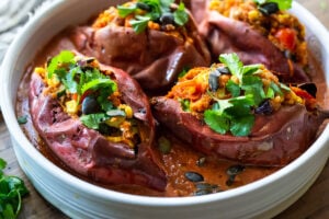 These Veggie-loaded, Baked Sweet Potatoes are infused with Oaxcan flavors, served over optional Mole Sauce. Healthy, flavorful and perfect for Sunday meal prep. Vegan-adaptable! Gluten-free. #bakedsweetpotatoes #sweetpotatoes #vegandinner #mealprep #veganrecipe
