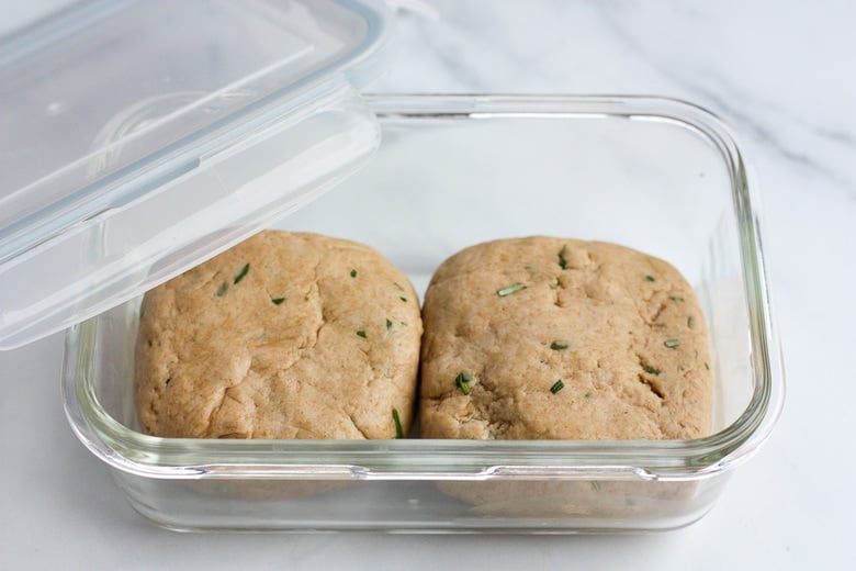 two separate balls of sourdough cracker dough in airtight glass container to be put in fridge.