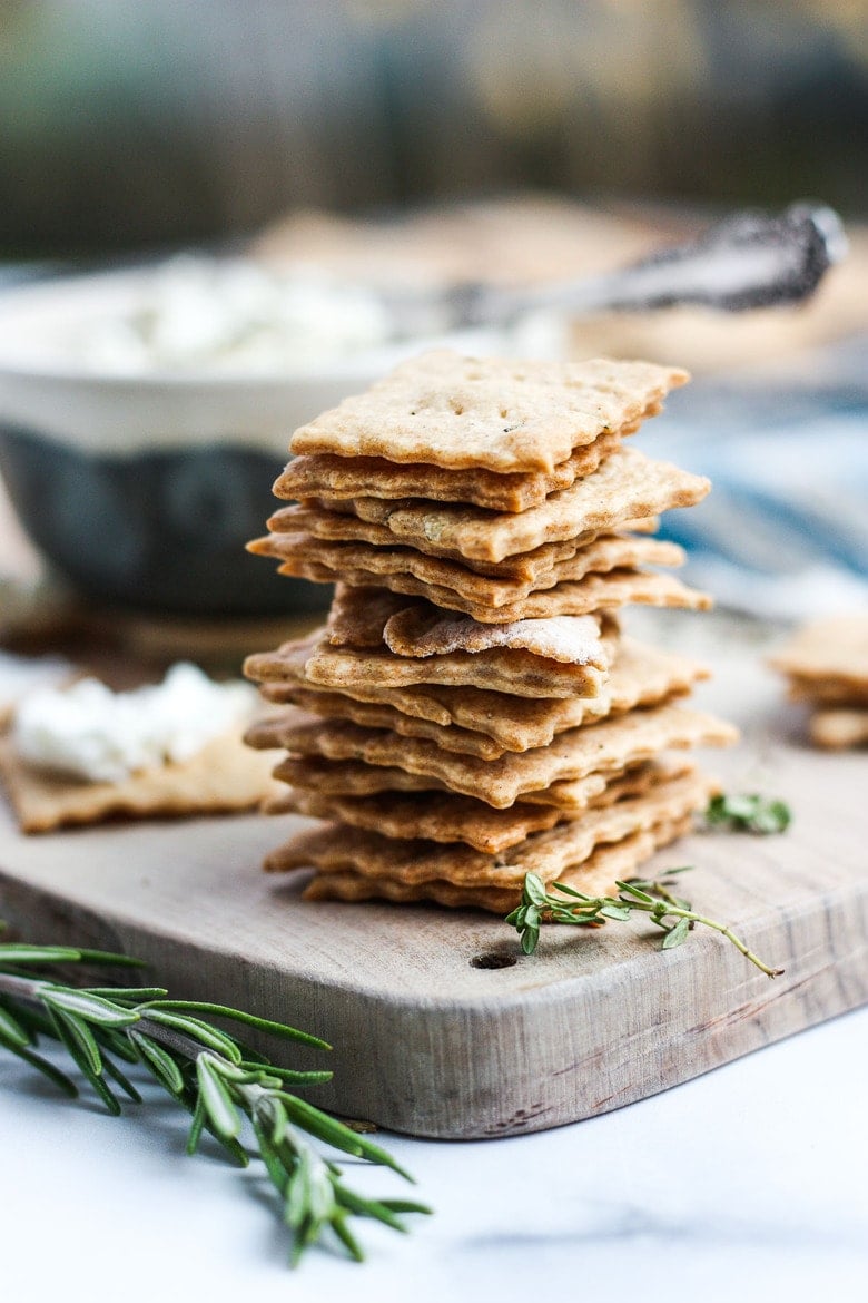 stack of homemade sourdough crackers piled up on wood board.