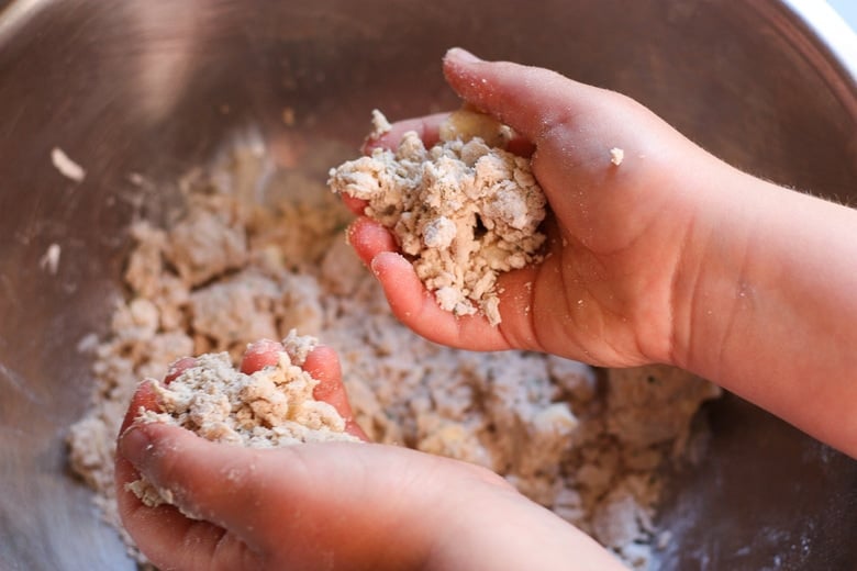 using hands to mix the dough for homemade sourdough crackers.