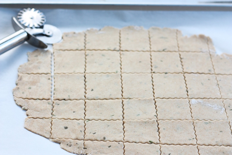 cutting out sourdough crackers with a pizza cutter.