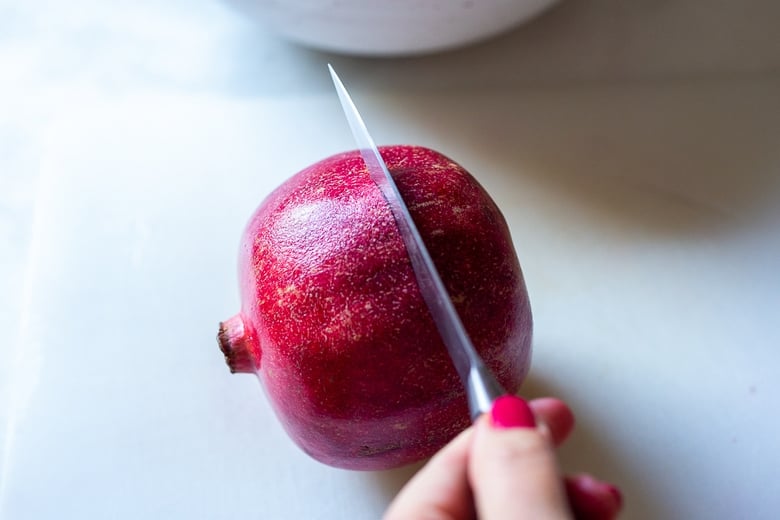 score the pomegranate with a sharp knife around the diameter