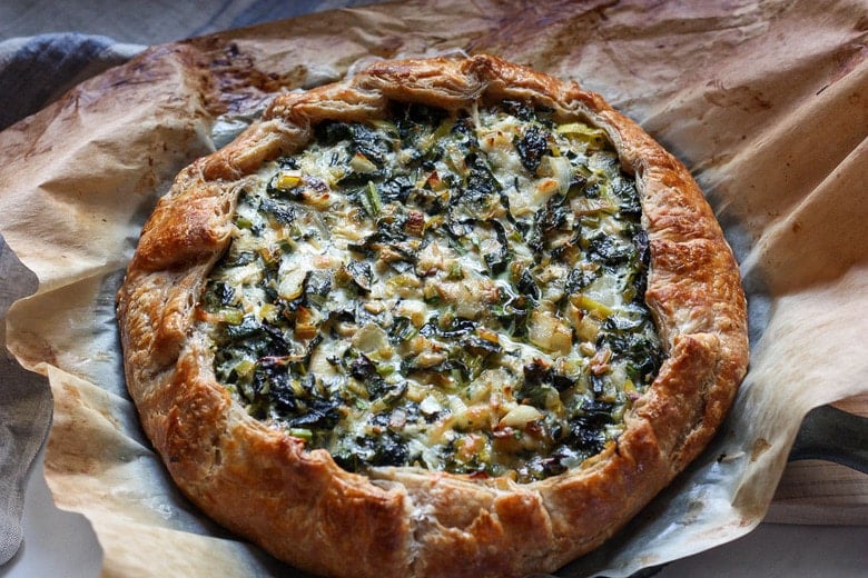 Beautiful and delicious Savory Leek Galette.   Made with a free-formed tender flakey crust enclosing a luscious melt in your mouth succulent filling. Leeks and kale marry with gruyere and mascarpone making the perfect balance of decadent and wholesome! The Galette dough is the secret here! #galette #savorygalette #tart #leeks 