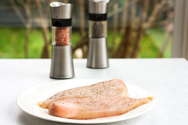 seasoning the chicken with salt and pepper