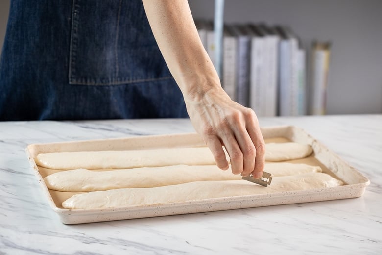 Using a lame (or sharp knife or razor blade), make 3-5 diagonal slashes into each piece of dough.