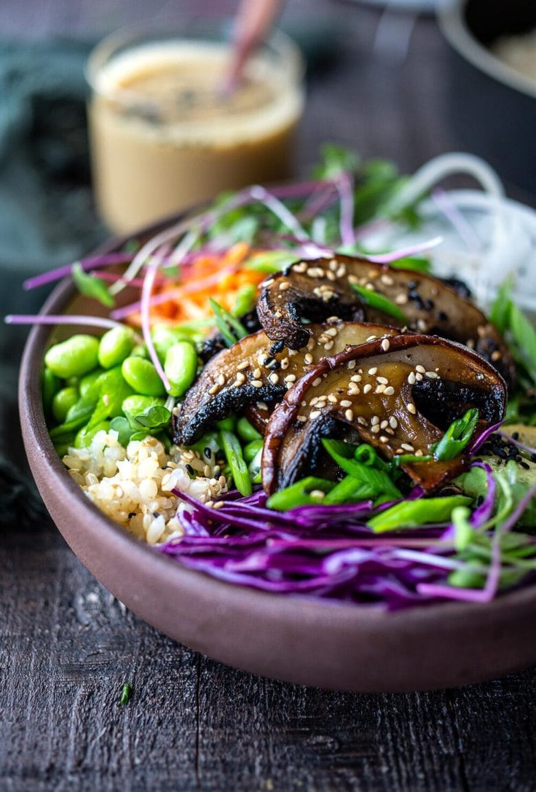 A flavorful Miso Mushroom Bowl with brown rice, avocado, cabbage, carrots, daikon, edamame and a Miso Ginger Dressing. Vegan and Gluten free. #bowl #veganbowl #vegandinner #mushroombowl