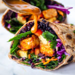 Scrumptious Thai Burrito with Peanut Sauce, baked peanut Tofu, black rice, spicy sriracha black beans and shredded crunchy veggies all wrapped up in a warm, whole wheat tortilla. #vegan #veganburrito #thaiburrito