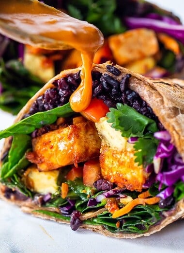 Scrumptious Thai Burrito with Peanut Sauce, baked peanut Tofu, black rice, spicy sriracha black beans and shredded crunchy veggies all wrapped up in a warm, whole wheat tortilla. #vegan #veganburrito #thaiburrito