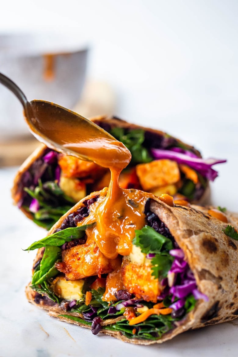 Scrumptious Thai Burrito with Peanut Sauce, baked peanut Tofu, black rice, spicy sriracha black beans and shredded crunchy veggies all wrapped up in a warm, whole wheat tortilla. #vegan #veganburrito #thaiburrito 