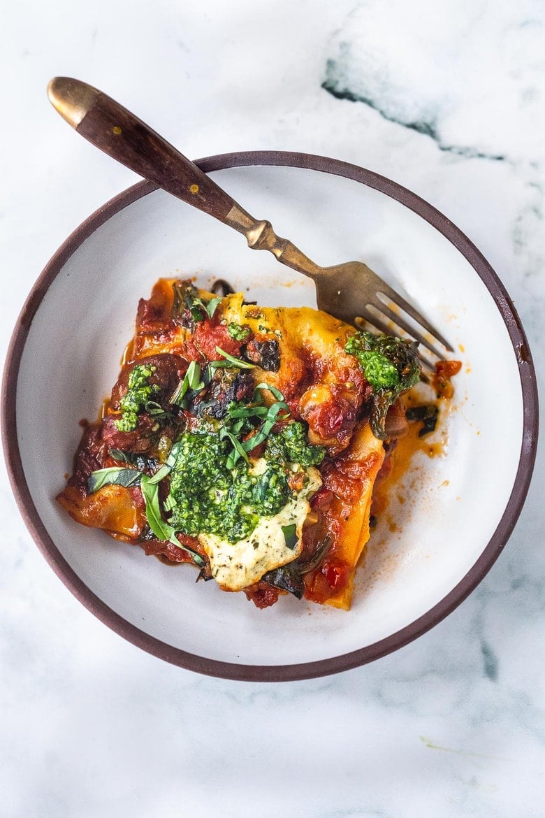 This Vegan Lasagna is made with a robust mushroom-spinach bolognese sauce, fresh basil, vegan ricotta and no-boil lasagna noodles, topped off with a creamy marinara sauce, drizzled with Arugula Basil Pesto. Vegan comfort food at its best! #veganlasagna #vegandinnerrecipes #vegan #lasagna #mushroombolognese 