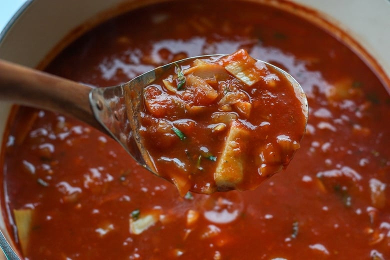 simmering the soup - a ladle holding up a spoonful.