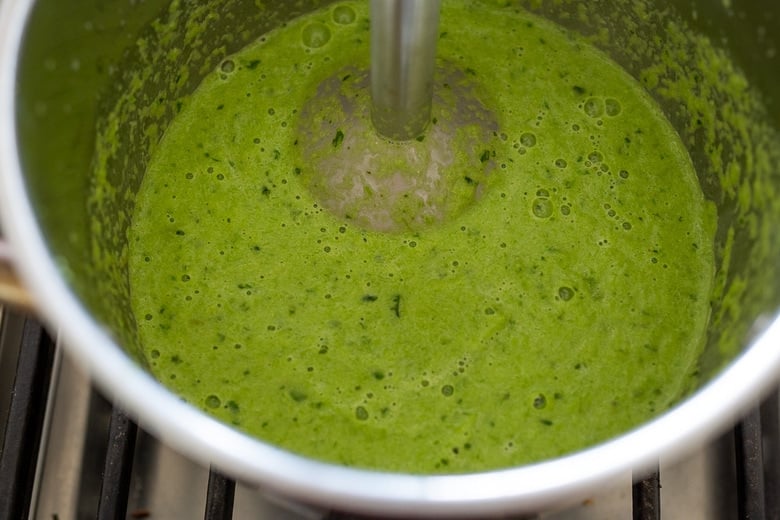 immersion blender in pot making creamy asparagus basil sauce.