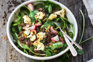 A fresh and flavorful Indian Spinach Salad with black lentils, roasted cauliflower and roasted radishes.  Caramelized shallots and a Tempered Seed Dressing give the salad amazing flavor, depth and crunchy texture. #spinachsalad #indiansalad #vegan