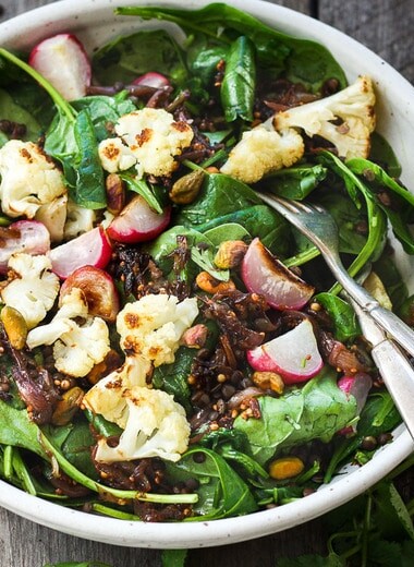 A fresh and flavorful Indian Spinach Salad with black lentils, roasted cauliflower and roasted radishes.  Caramelized shallots and a Tempered Seed Dressing give the salad amazing flavor, depth and crunchy texture. #spinachsalad #indiansalad #vegan