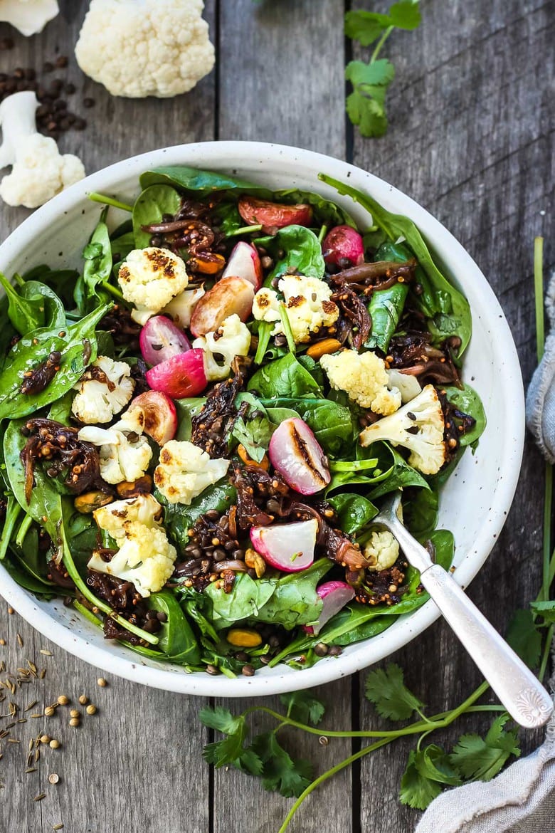 A fresh and flavorful Indian Spinach Salad with black lentils, roasted cauliflower and roasted radishes.  Caramelized shallots and a Tempered Seed Dressing give the salad amazing flavor, depth and crunchy texture. #spinachsalad #indiansalad #vegan