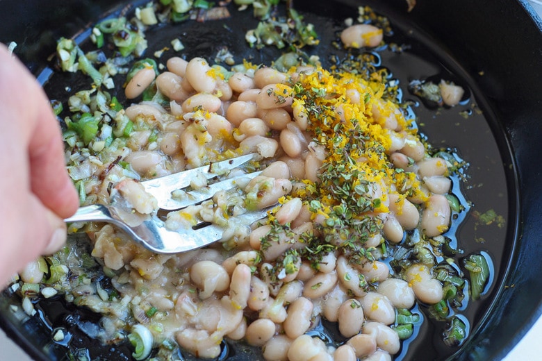 mashing the beans into the leeks to create a sauce 