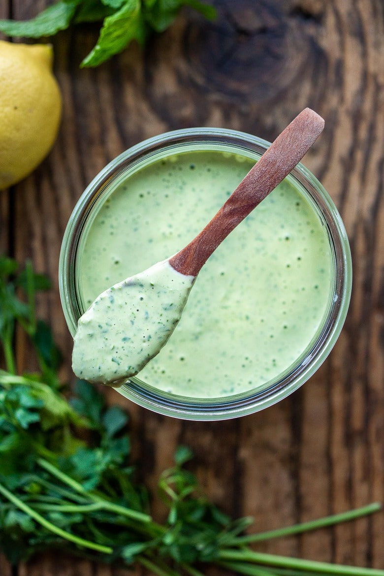 Flavorful Green Tahini Sauce made with tahini paste, fresh herbs, garlic, lemon and a few slices of green chilies. Perfect vegan condiment to serve with falafels, pita bread, shawarma, mezze platters! #tahinisauce #tahini #vegan