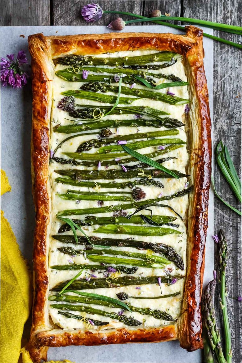 baked asparagus tart with puff pastry, garnished with chive blossoms, French tarragon.