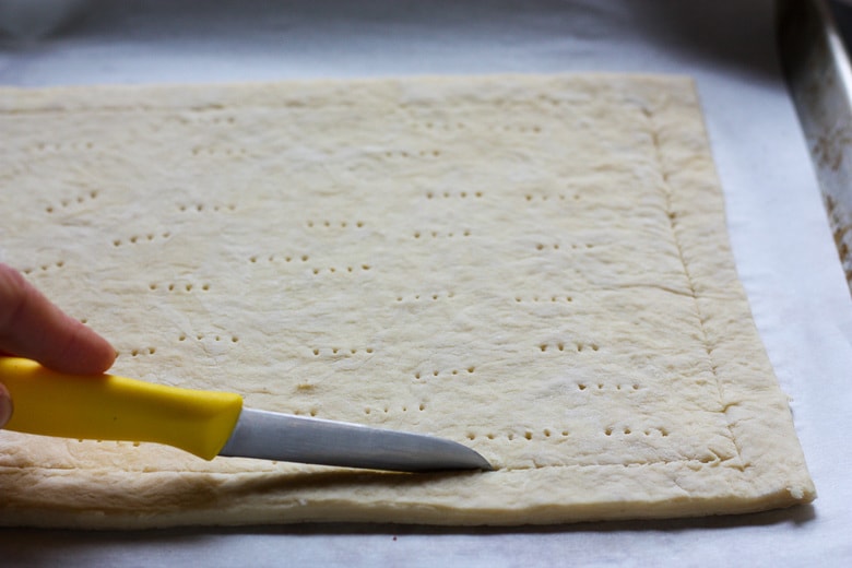 prepping the puff pastry by slicing a line 1 inch from the edge with a knife.