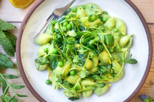 This Creamy Vegan Pea Pasta is lathered up in the most delicious, luscious sauce made with fresh (or frozen) English peas and mint without a lick of dairy! Happy little shells cradle a vibrant, creamy green sauce made up of peas and mint. #vegan #peapasta #veganpasta