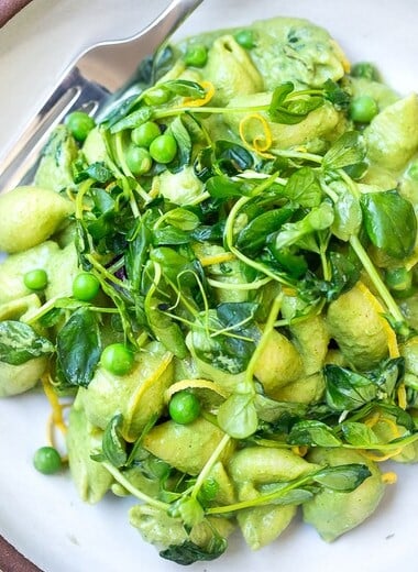 This Creamy Vegan Pea Pasta is lathered up in the most delicious, luscious sauce made with fresh (or frozen) English peas and mint without a lick of dairy! Happy little shells cradle a vibrant, creamy green sauce made up of peas and mint. #vegan #peapasta #veganpasta