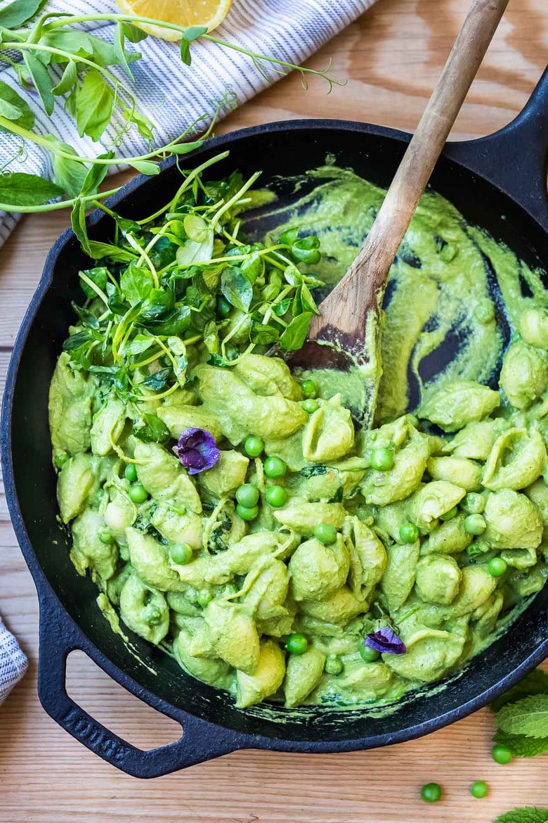 This Creamy Vegan Pea Pasta is lathered up in the most delicious, luscious sauce made with fresh (or frozen) English peas and mint without a lick of dairy! Happy little shells cradle a vibrant, creamy green sauce made up of peas and mint. #vegan #peapasta #veganpasta
