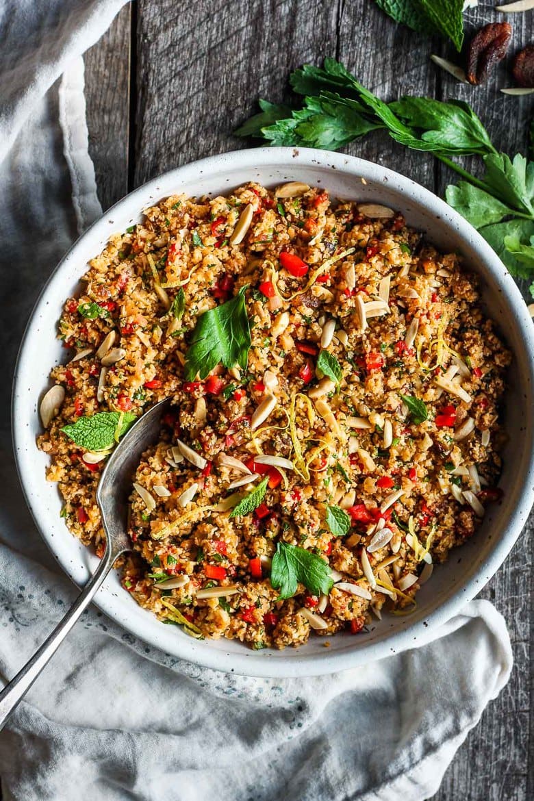 Moroccan Cauliflower "Couscous" made with riced cauliflower, dried apricots, toasted almonds and fragrant Moroccan spices, tossed with fresh parsley, mint and a lemon honey drizzle.   Gluten-free, healthy and vibrantly flavorful! Vegan-adaptable. #cauliflower #cauliflowerrice #couscous