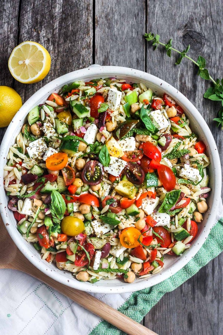 This healthy Greek Pasta Salad is the perfect make-ahead pasta salad for summertime picnics, bbqs, potlucks and easy dinners.  A hearty ratio of fresh veggies combined with tender orzo pasta, chickpeas tossed in the tastiest Greek salad dressing.#greekpastasalad