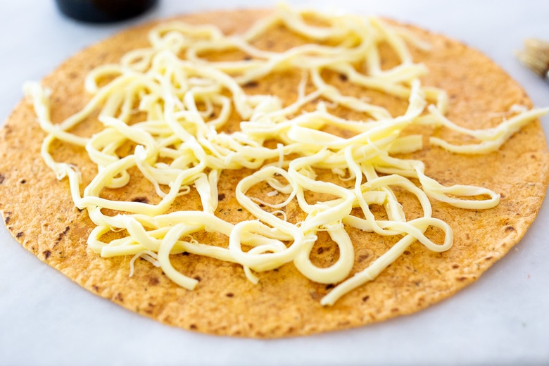 assembling the quesadillas with cheese on a tortilla