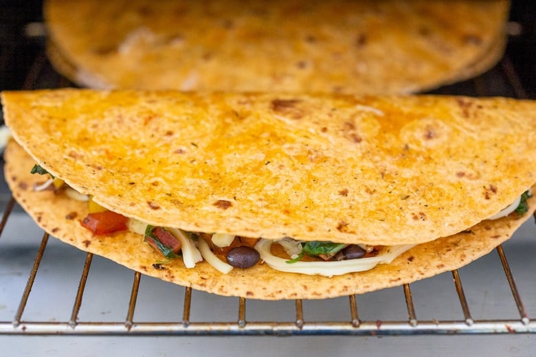 vegetable quesadilla going into the oven to bake, on the oven rack.