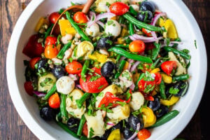 Antipasto Salad with white beans, aritchoke hearts, olives, fresh veggies, and lots of herbs, tossed in a simple Italian dressing. Vegan and Low Carb adaptable!