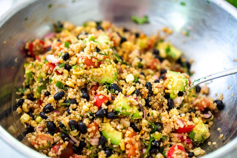 black bean quinoa salad being mixed in a bowl.