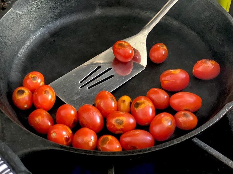 tomatoes being charred in a cast iron skillet