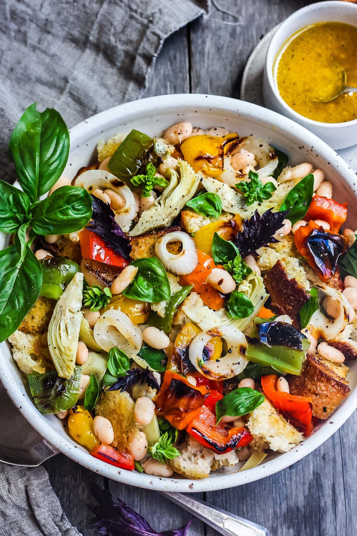 Delicious Grilled Panzanella Salad with colorful sweet bell peppers, artichoke hearts, and white beans tossed in a flavorful white balsamic dressing.  Make it on the barbecue for an easy outdoor summer meal with your favorite grilled protein!  Vegan!