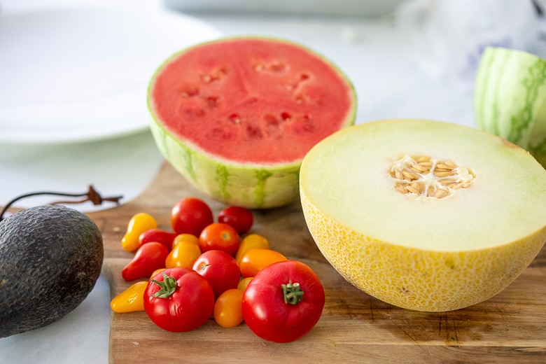 tomatoes and melons on a cutting board