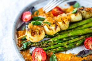 Grilled Scallops, marinated with olive oil, orange zest, coriander, salt and pepper, topped with Charred Tomato Vinaigrette. A delicious summer dinner that is fast, easy, light, refreshing and elegant! #grilledscallops
