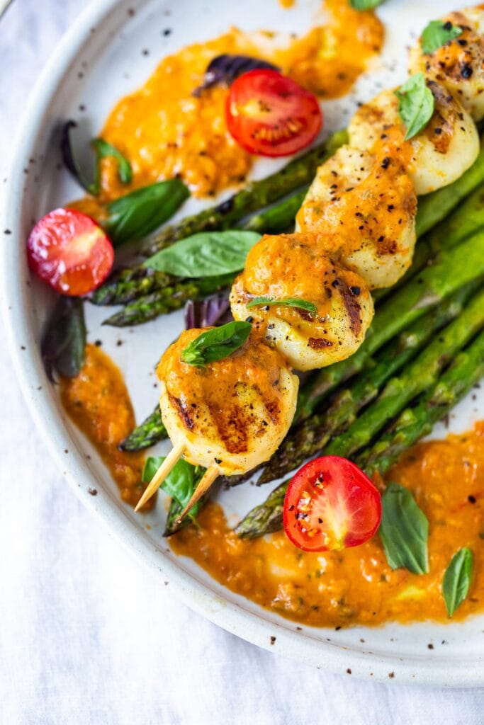 grilled scallops on skewers on bed of grilled asparagus, with tomato vinaigrette and fresh cherry tomatoes and basil.